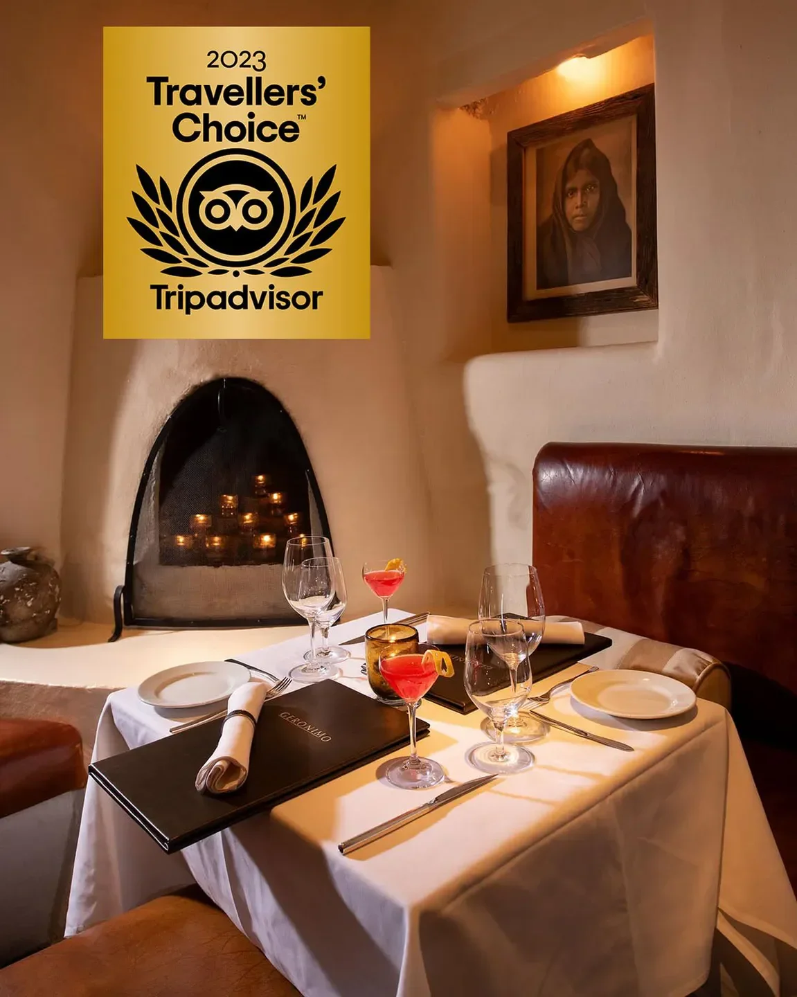 Cozy dining setting at Geronimo restaurant in Santa Fe, featuring cocktails and fireplace.