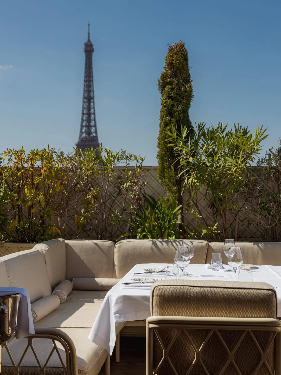 Gigi Paris rooftop dining with Eiffel Tower view, set table and lush greenery.