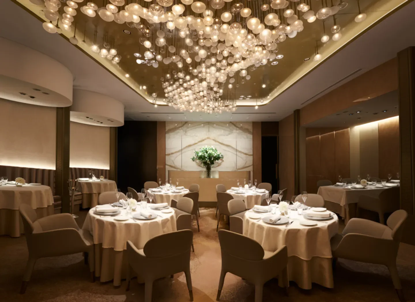 Elegant dining room interior at Ginza L'ecrin in Tokyo with unique light fixture.