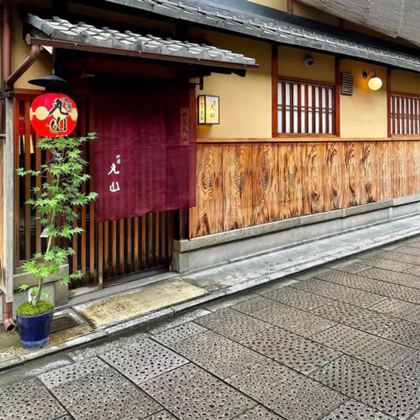 Entrance to Gion Okada restaurant in Kyoto, with traditional Japanese architecture and red lantern.