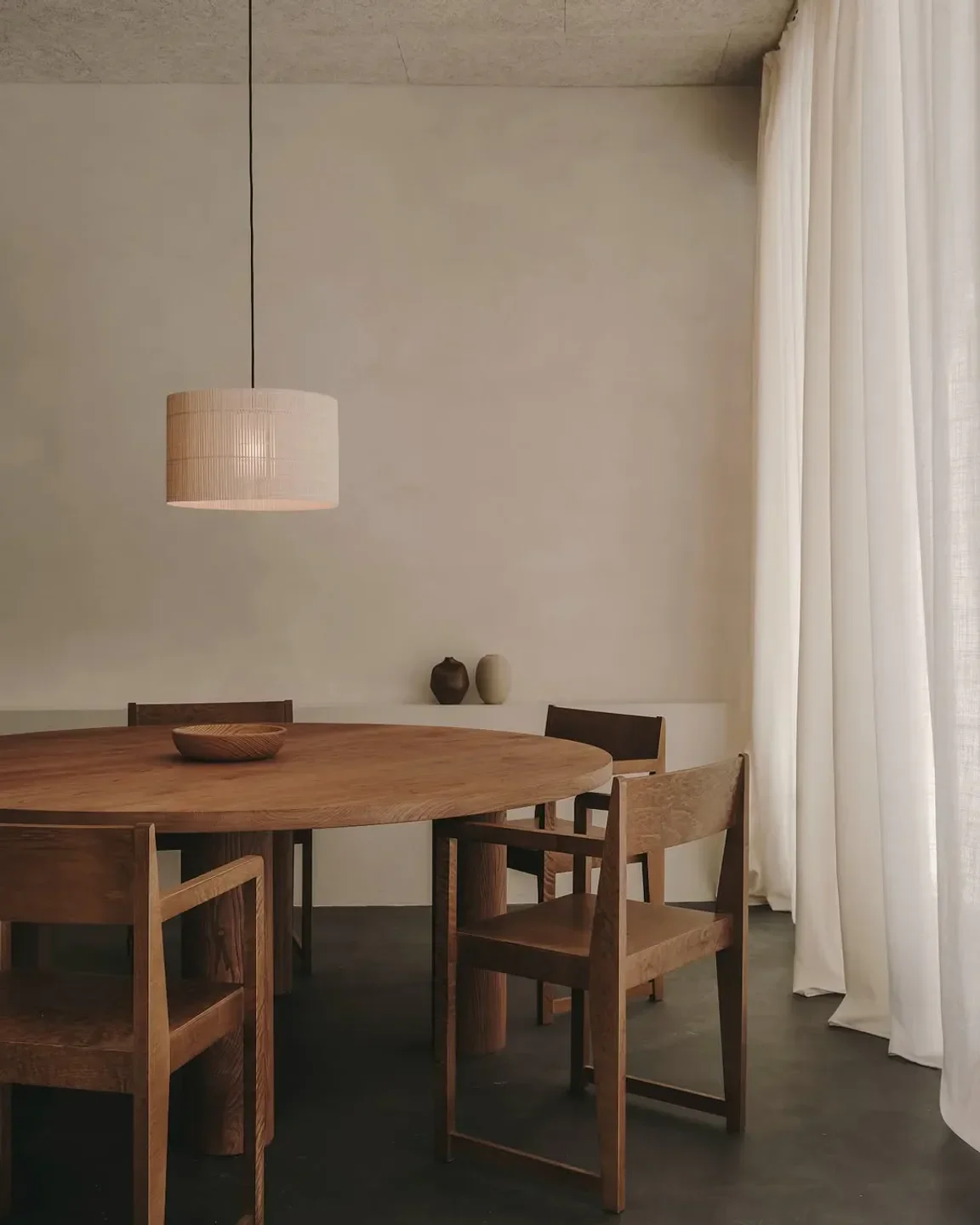 Dining space at Gofio restaurant in Madrid, featuring wooden table and chairs with curtains.