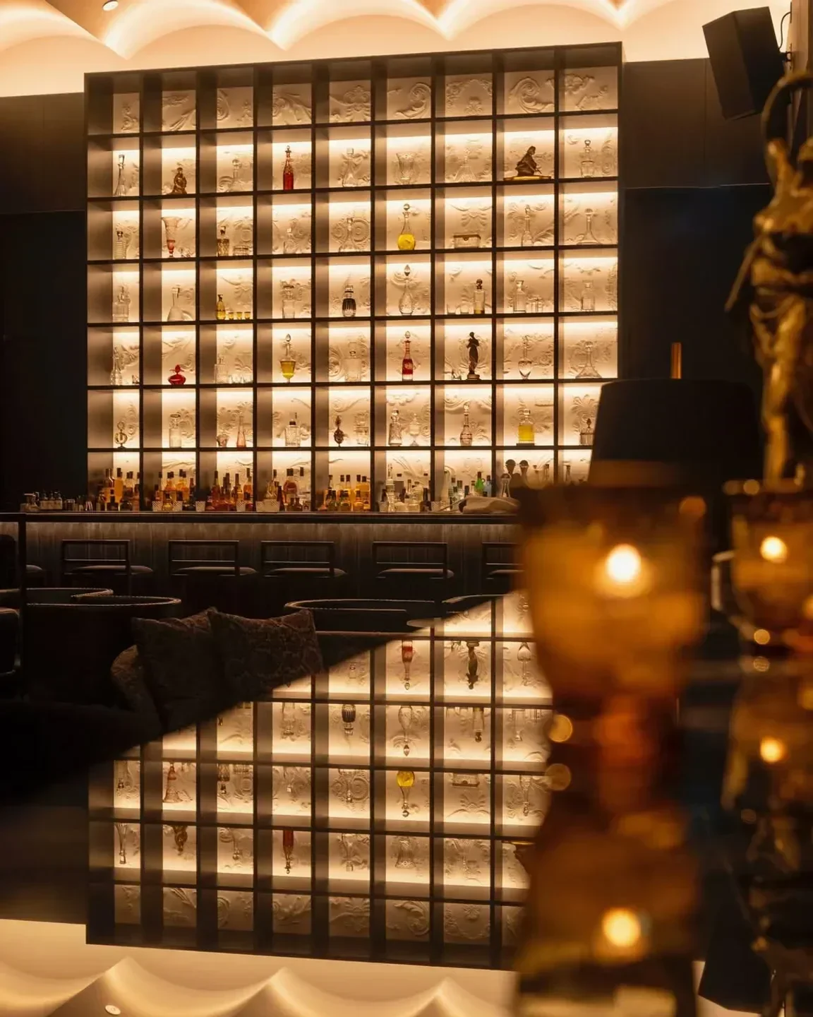 Interior of Gold Bar in Tokyo. Lit-up shelf with spirits and artistic decor.