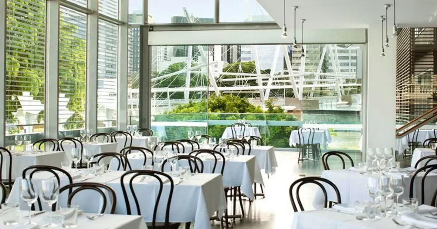 Elegant interior of GOMA Restaurant in Brisbane, with city views and white tablecloths.