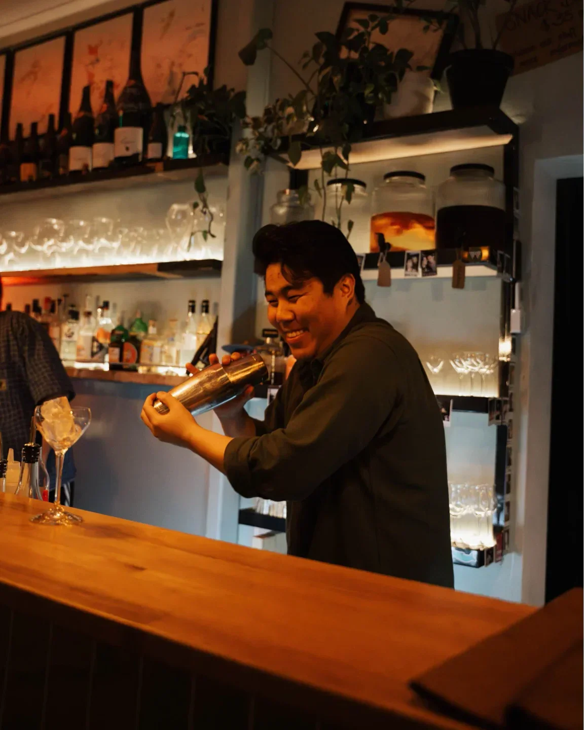 Smiling bartender at Good Gilbert in Adelaide mixing a cocktail behind the bar.