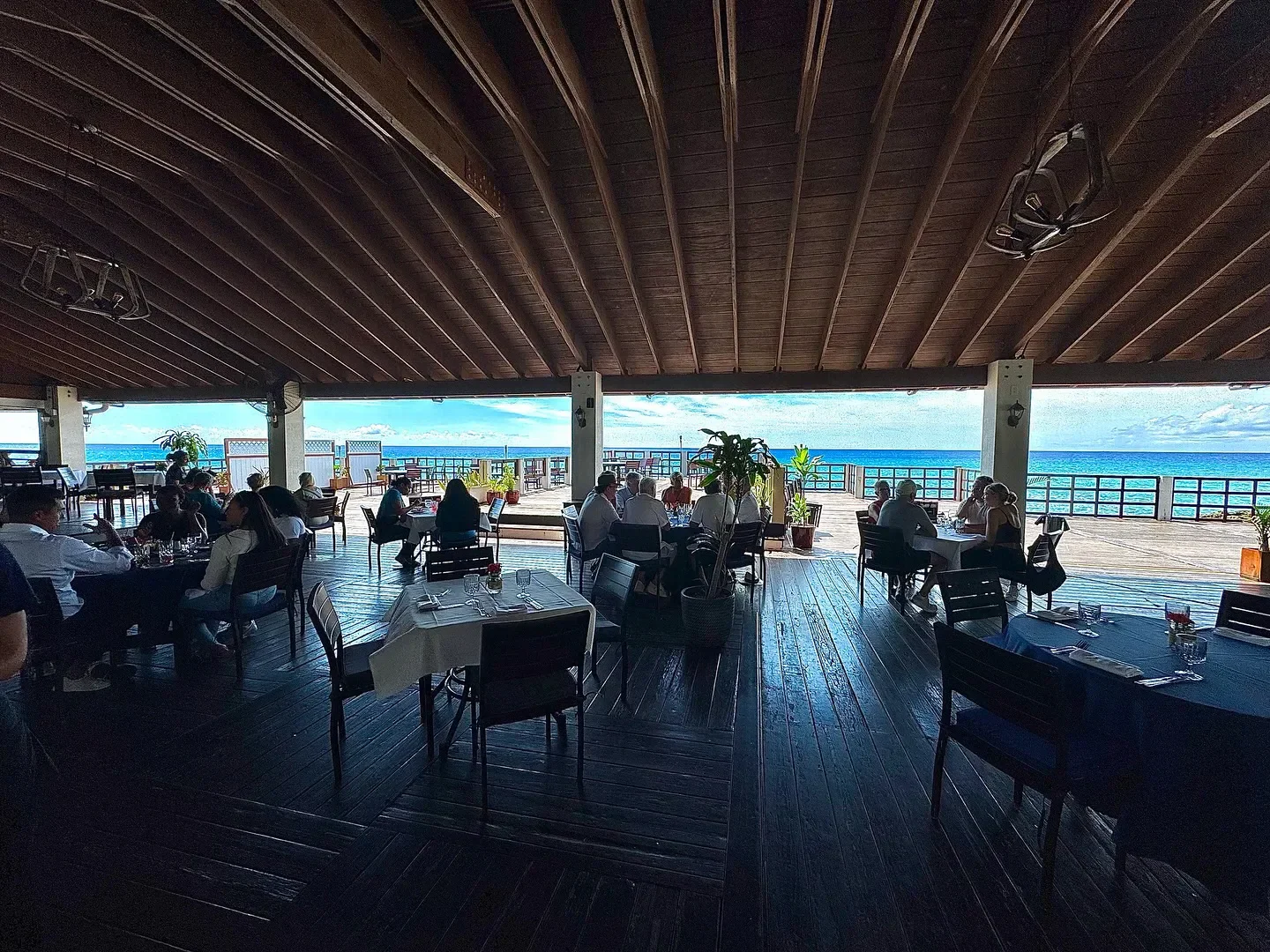 Dining at Grand Old House restaurant in Grand Cayman with ocean view and wood decking