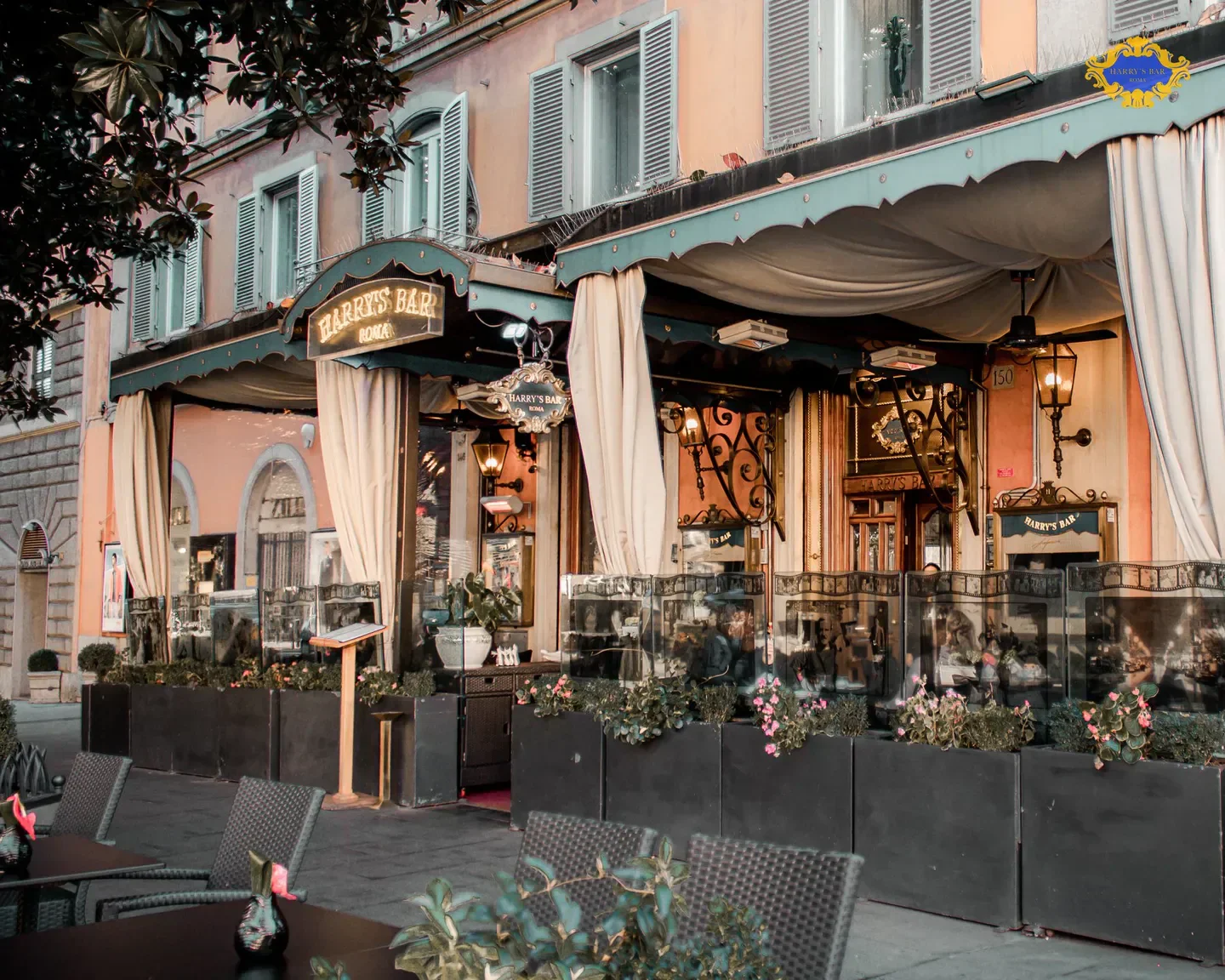 Exterior view of Harry's Bar in Rome, with outdoor seating and floral details.
