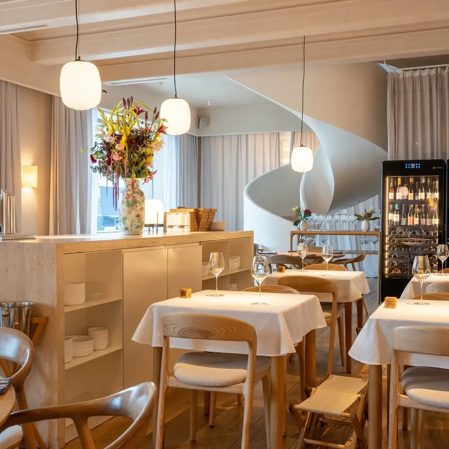 Elegant interior of Harvest - Харвест restaurant in St Petersburg, featuring spiral staircase and tables.