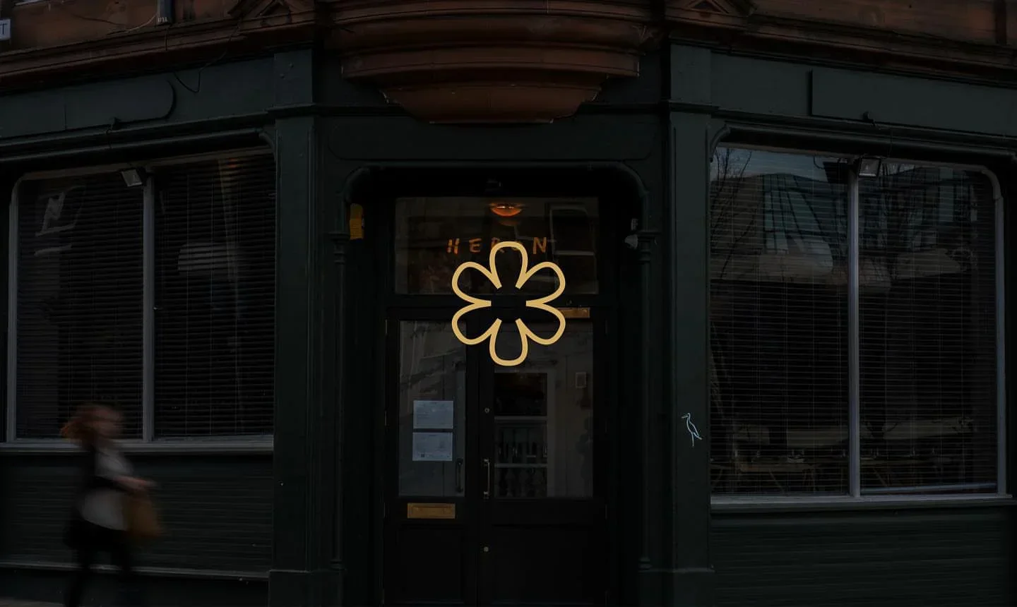 Entrance to Heron restaurant in Edinburgh, featuring a floral neon sign and dark exterior.
