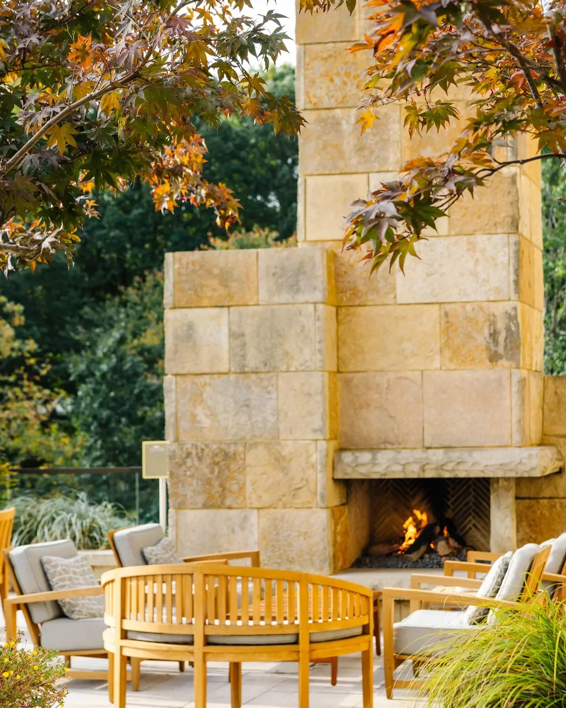 Outdoor fireplace and seating area at Herons restaurant in Raleigh, surrounded by fall foliage.