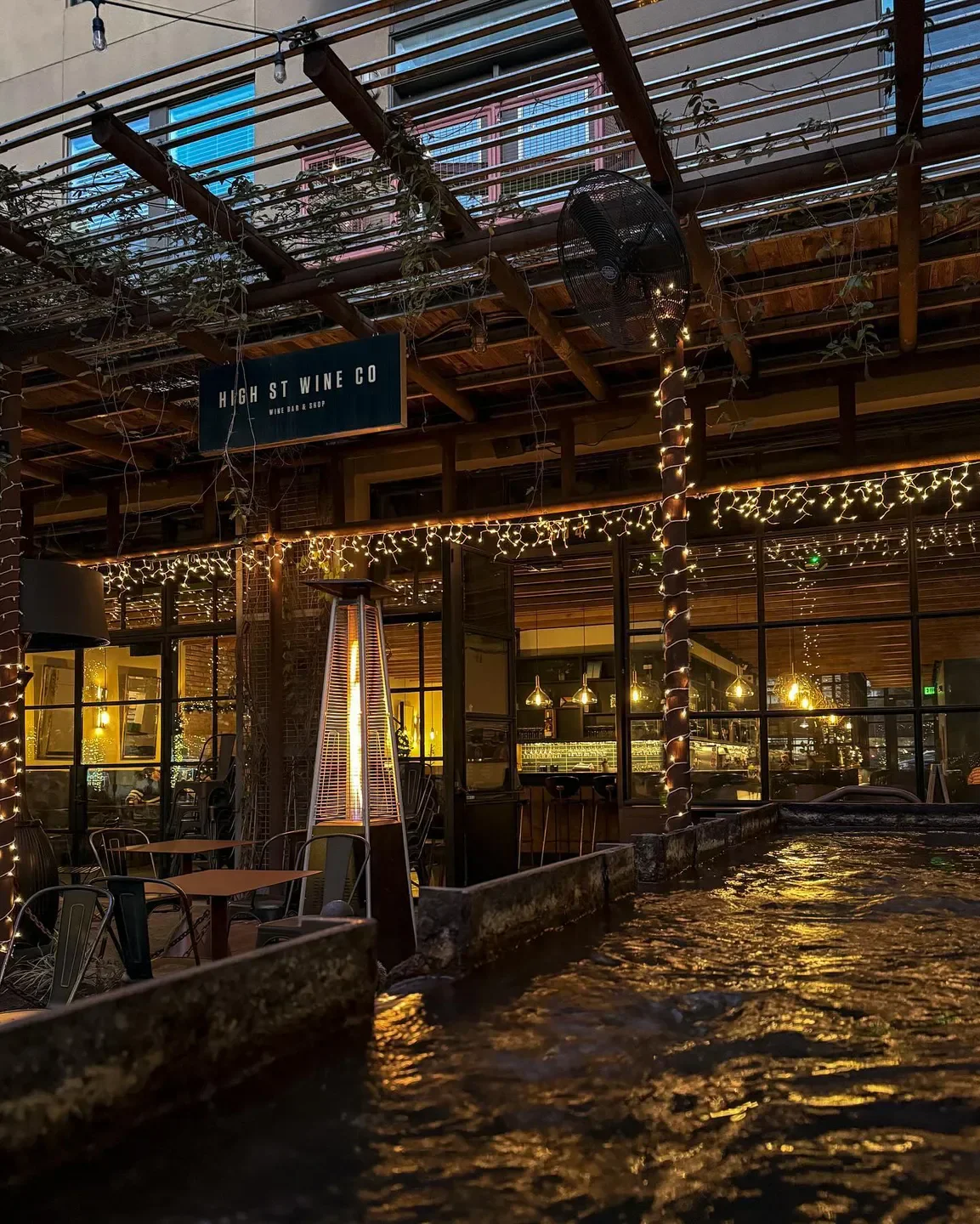 Outdoor patio at High Street Wine Co. in San Antonio, featuring water and string lights.