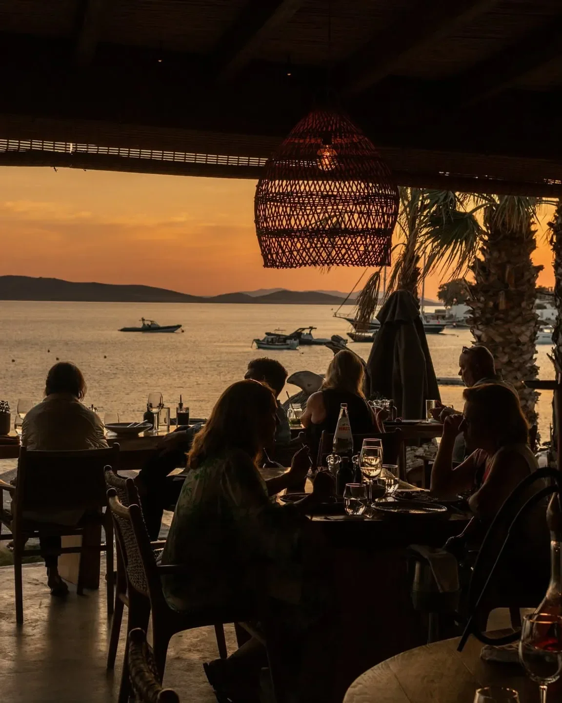 Dining at Hippie Fish in Mykonos, Greece, with sunset view over the Aegean Sea.