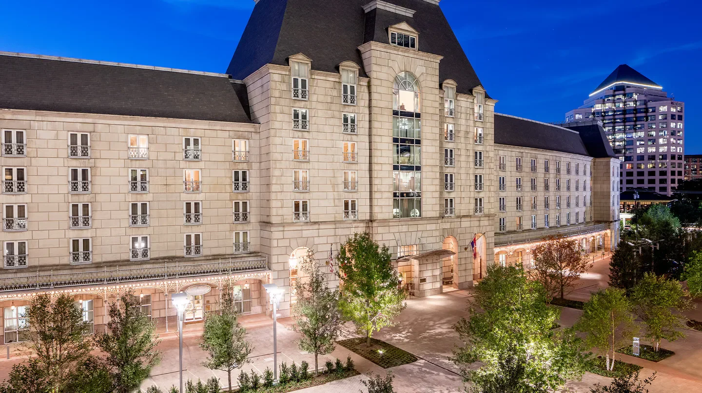 Hotel Crescent Court in Dallas at dusk, showcasing architecture and lush landscaping.