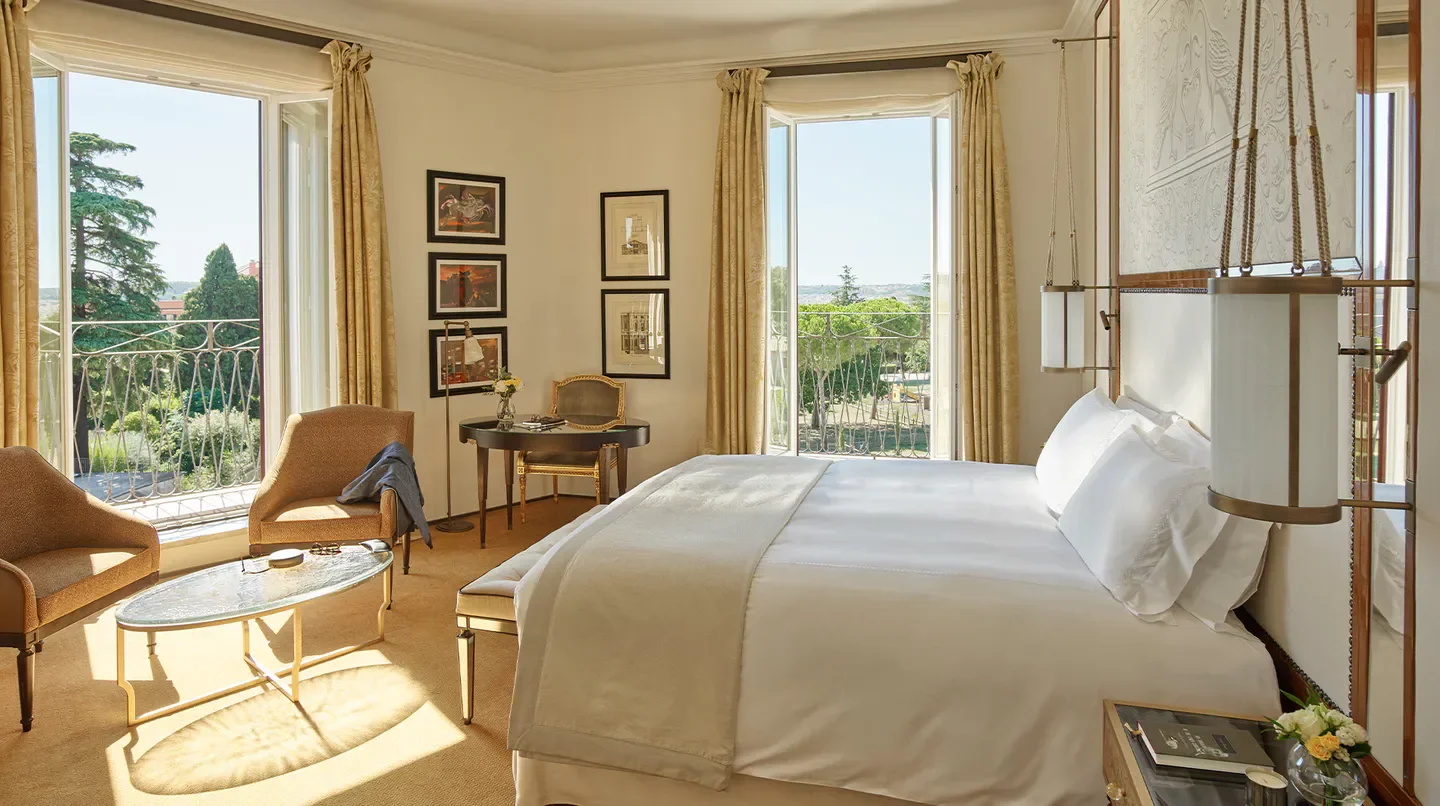 Elegant bedroom at Hotel Eden in Rome, featuring a balcony overlooking the city.