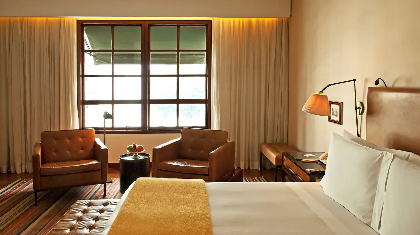 Cozy bedroom interior at Hotel Fasano São Paulo, featuring leather armchairs and natural light.