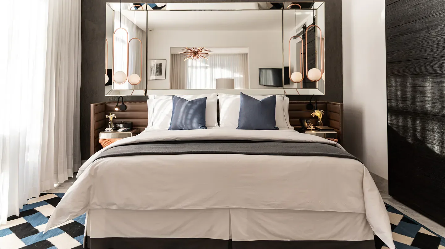 Hotel Matilda in San Miguel de Allende, stylish bedroom with large mirror and cozy bedding.