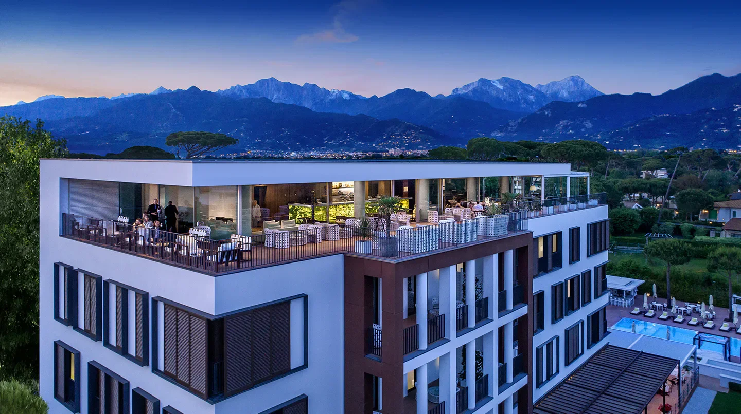 Hotel Principe Forte dei Marmi in Florence, scenic rooftop view at dusk with mountain backdrop.