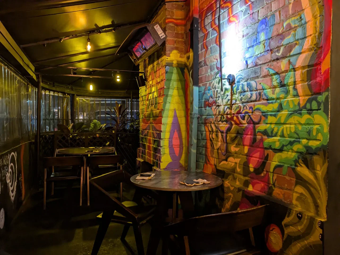 Colorful interior of Humo Negro restaurant in Bogota, featuring mural and seating area.