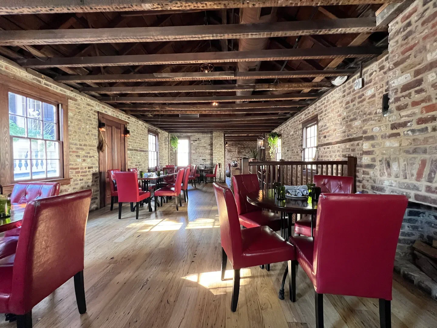 Interior of Husk restaurant in Charleston, featuring red chairs and brick walls.