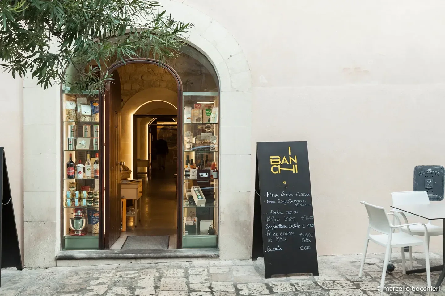 Entrance of I Banchi restaurant in Sicily, with menu board and inviting doorway.