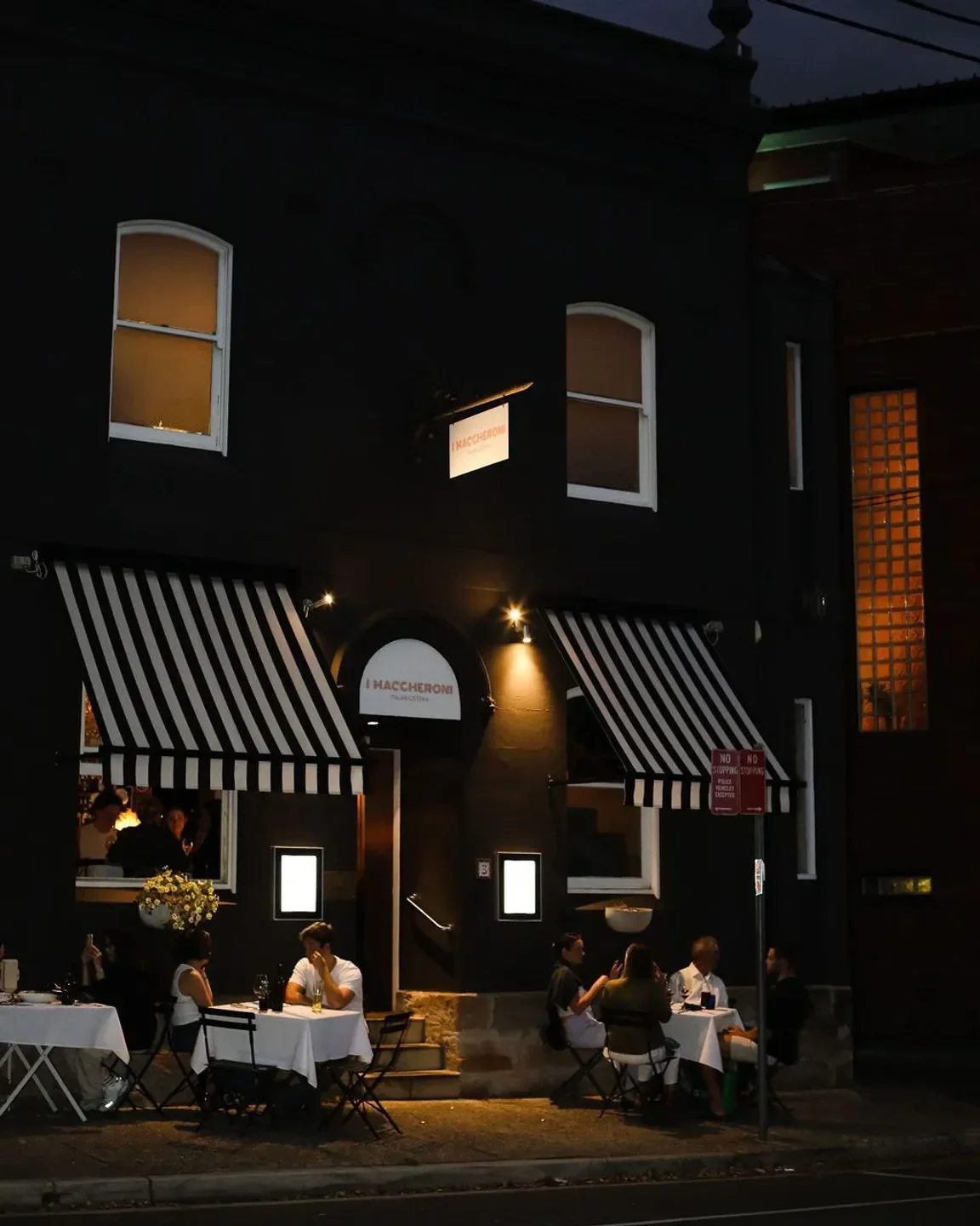 Outdoor dining at I Maccheroni restaurant in Sydney, featuring striped awnings and patrons.