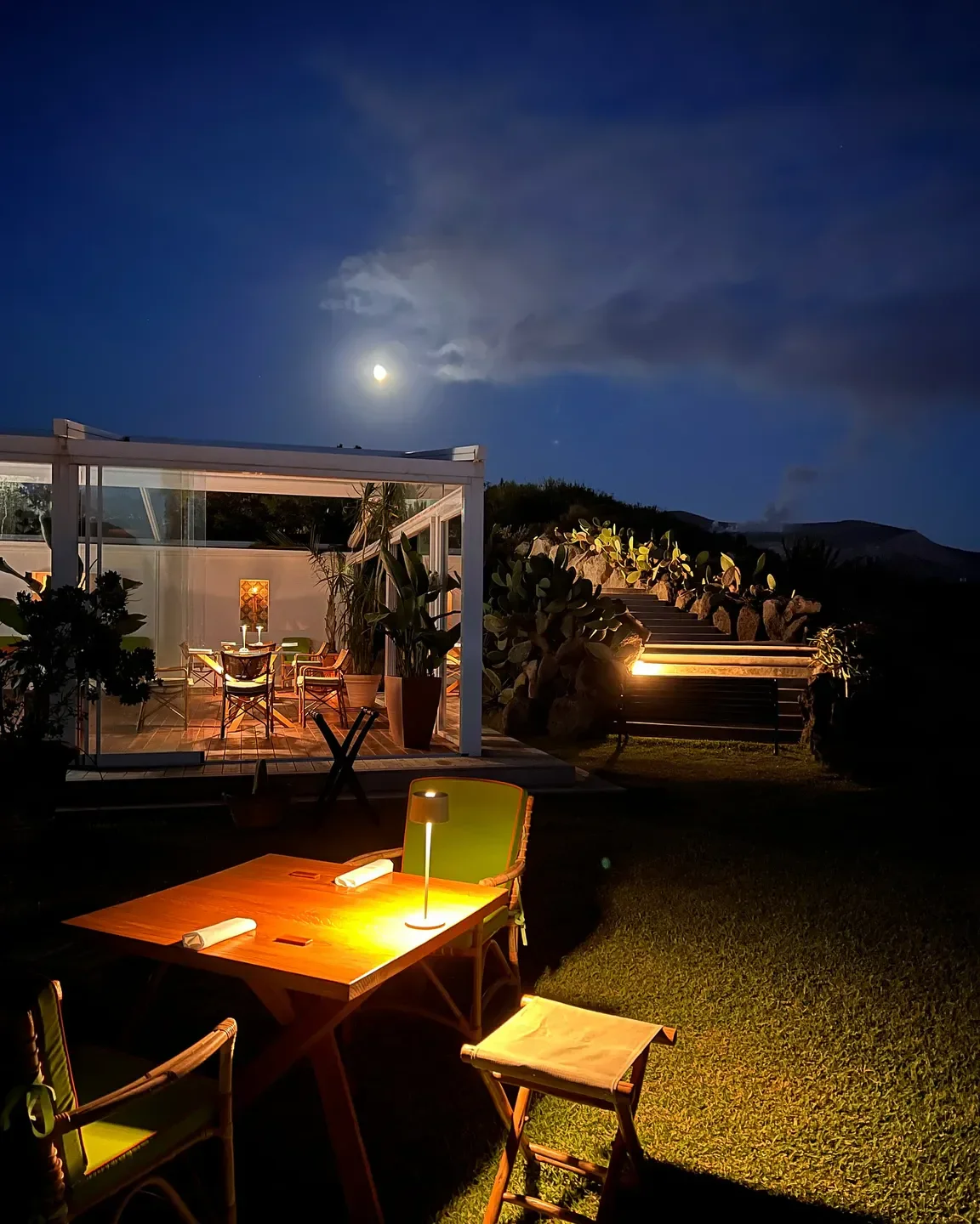 Outdoor dining at I Tenerumi restaurant in Sicily, illuminated by moonlight.