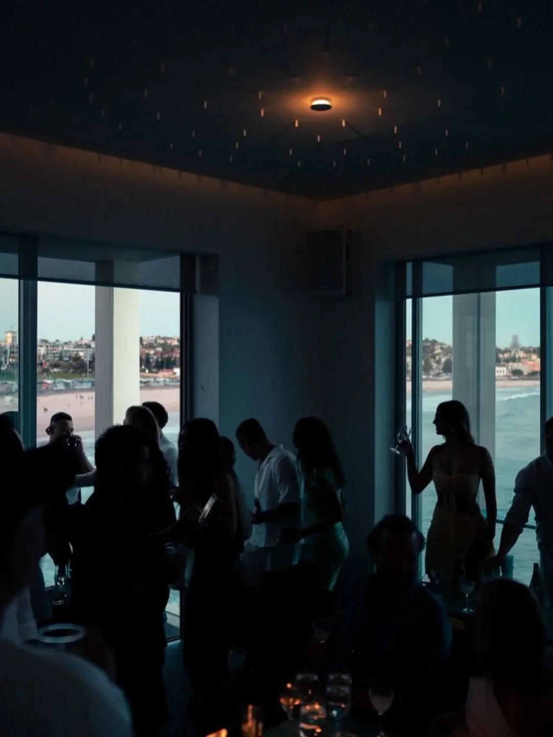 Atmospheric dining ambiance at Icebergs Dining Room & Bar in Sydney, Australia, with a view of the beach through the windows