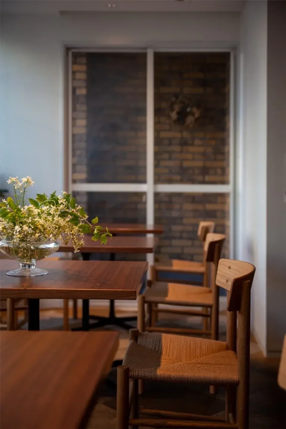 Interior of IDÉAL bistro in Osaka, featuring wooden tables and chairs, and a floral centerpiece.