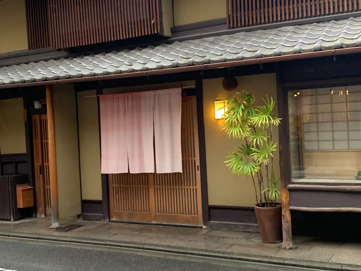 Exterior of Iida restaurant in Kyoto, Japan, with traditional architecture and greenery.