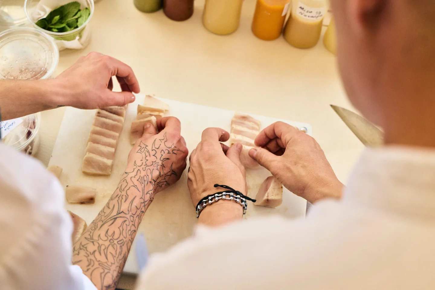 Chefs preparing raw fish slices at Ikisaki restaurant in the city, showcasing culinary skill.