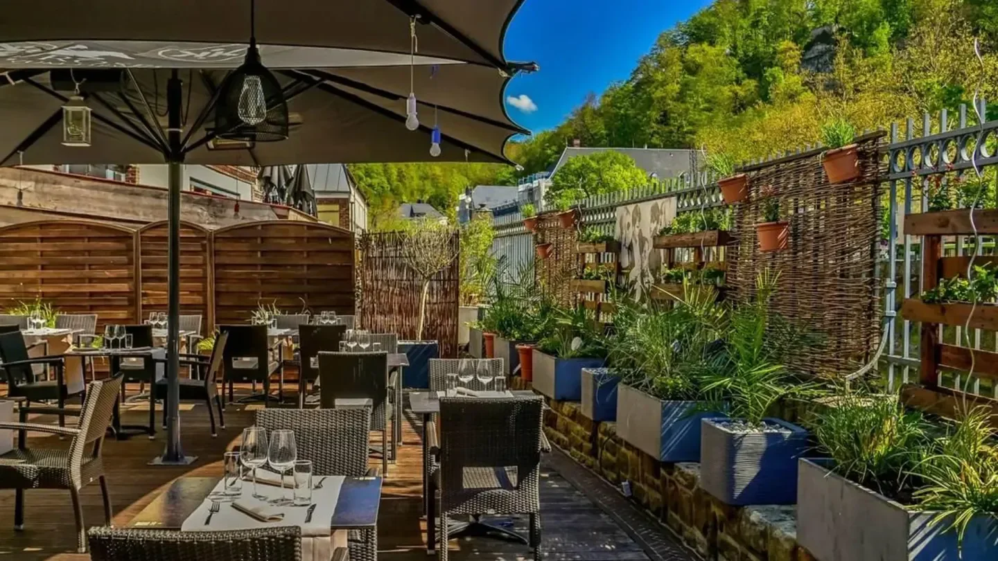 Outdoor dining area at Ikki restaurant in Luxembourg with greenery and mountain view.
