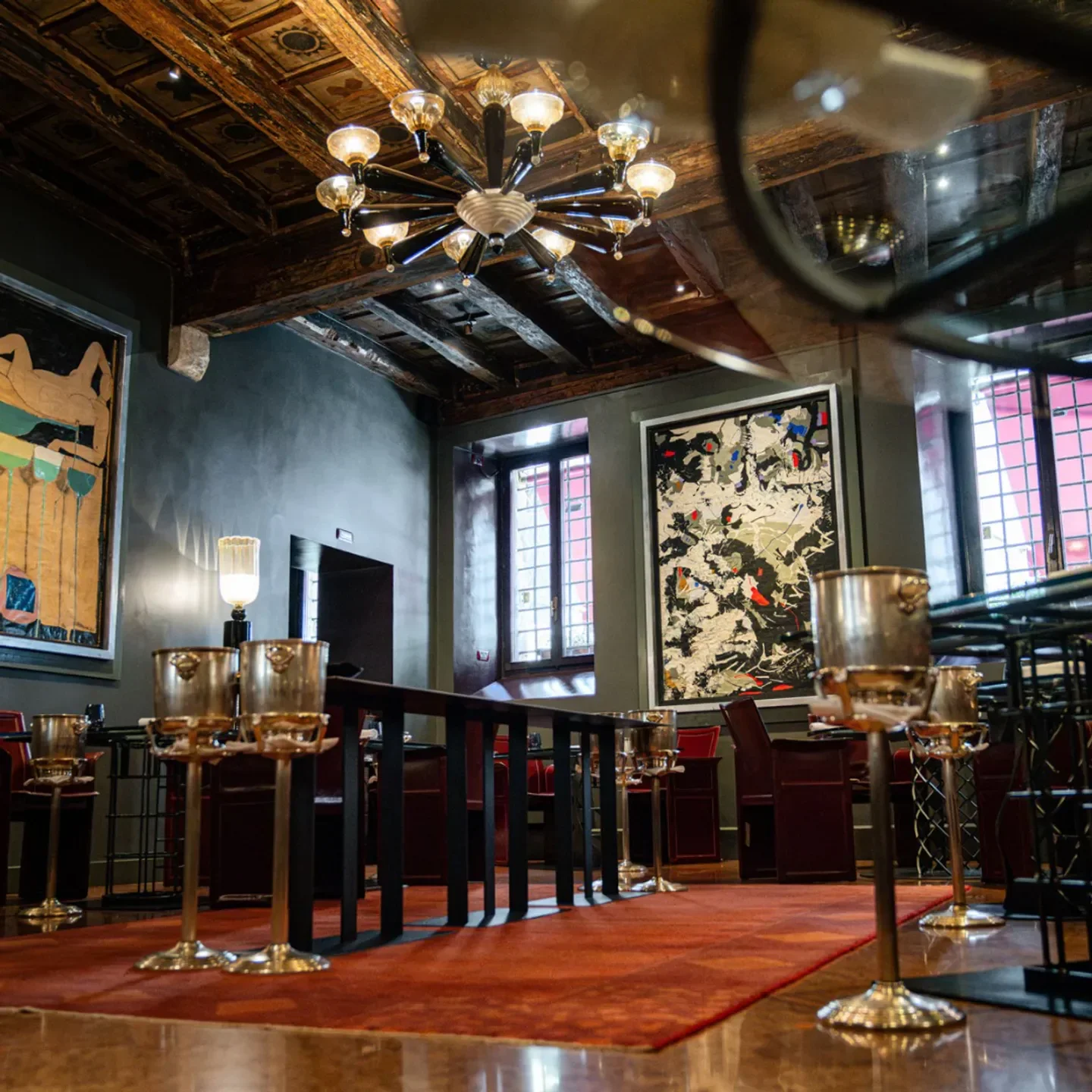 Elegant interior of Il Desco restaurant in Verona, featuring art and a chandelier.