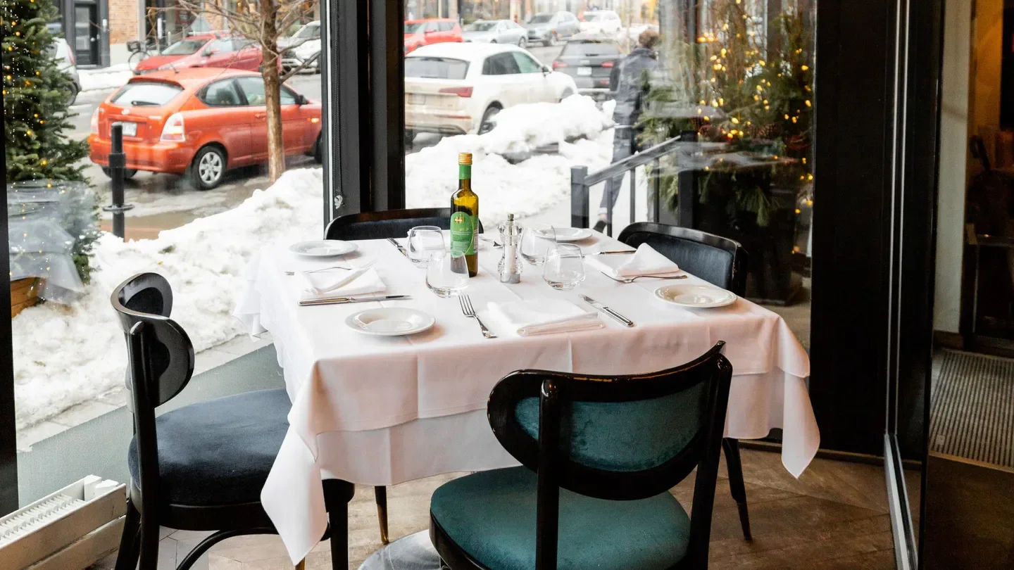 Table setting inside Il Pagliaccio restaurant in Montreal, with a snowy street view.