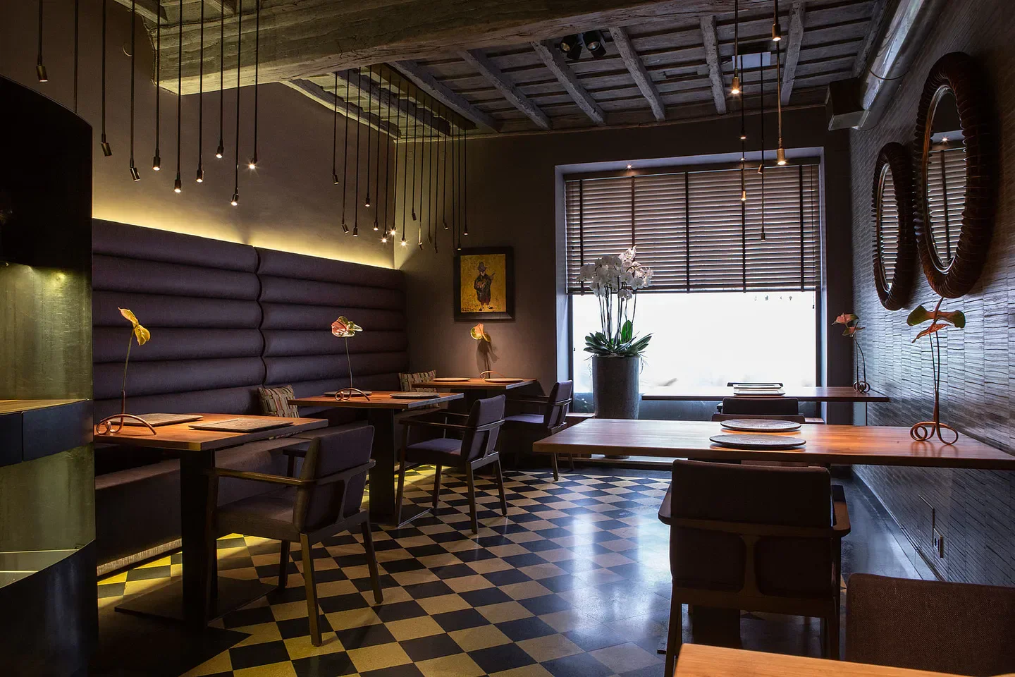 Stylish interior of Il Pagliaccio restaurant in Rome with dim lighting and checkered floors.