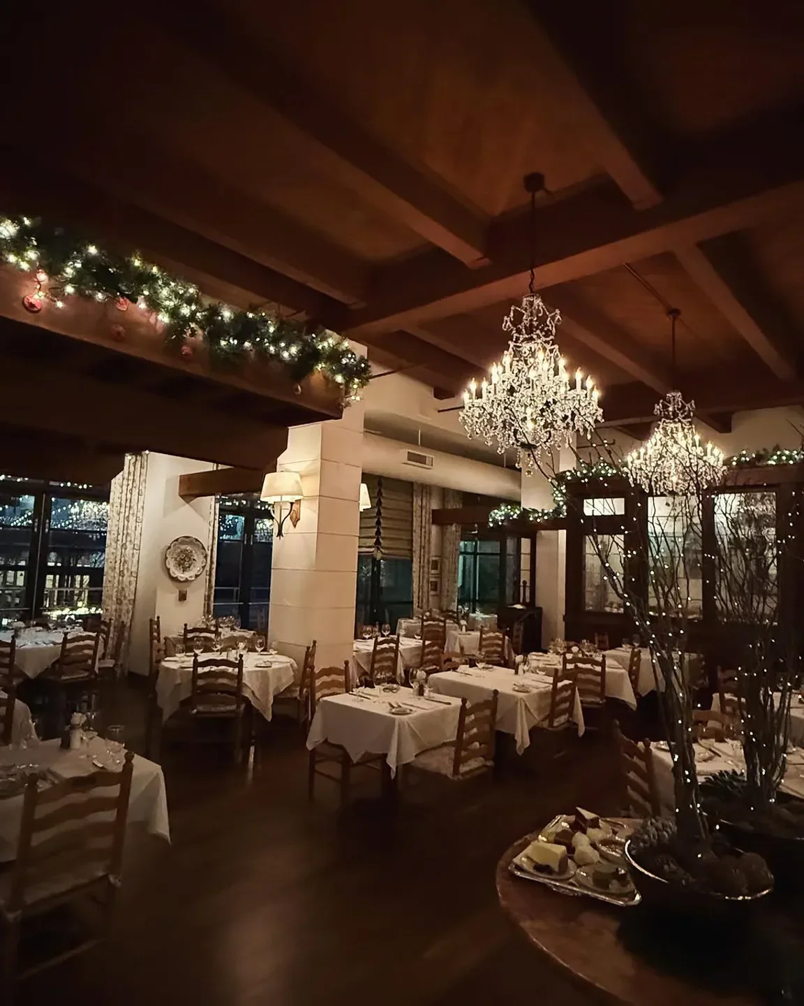 Cozy dining room at Il Terrazzo Carmine in Seattle, with chandeliers and decorated for the holidays.
