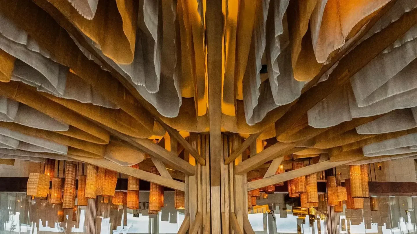 Unique ceiling decor at Ilios nightclub in Tulum, featuring wooden beams and hanging lights.