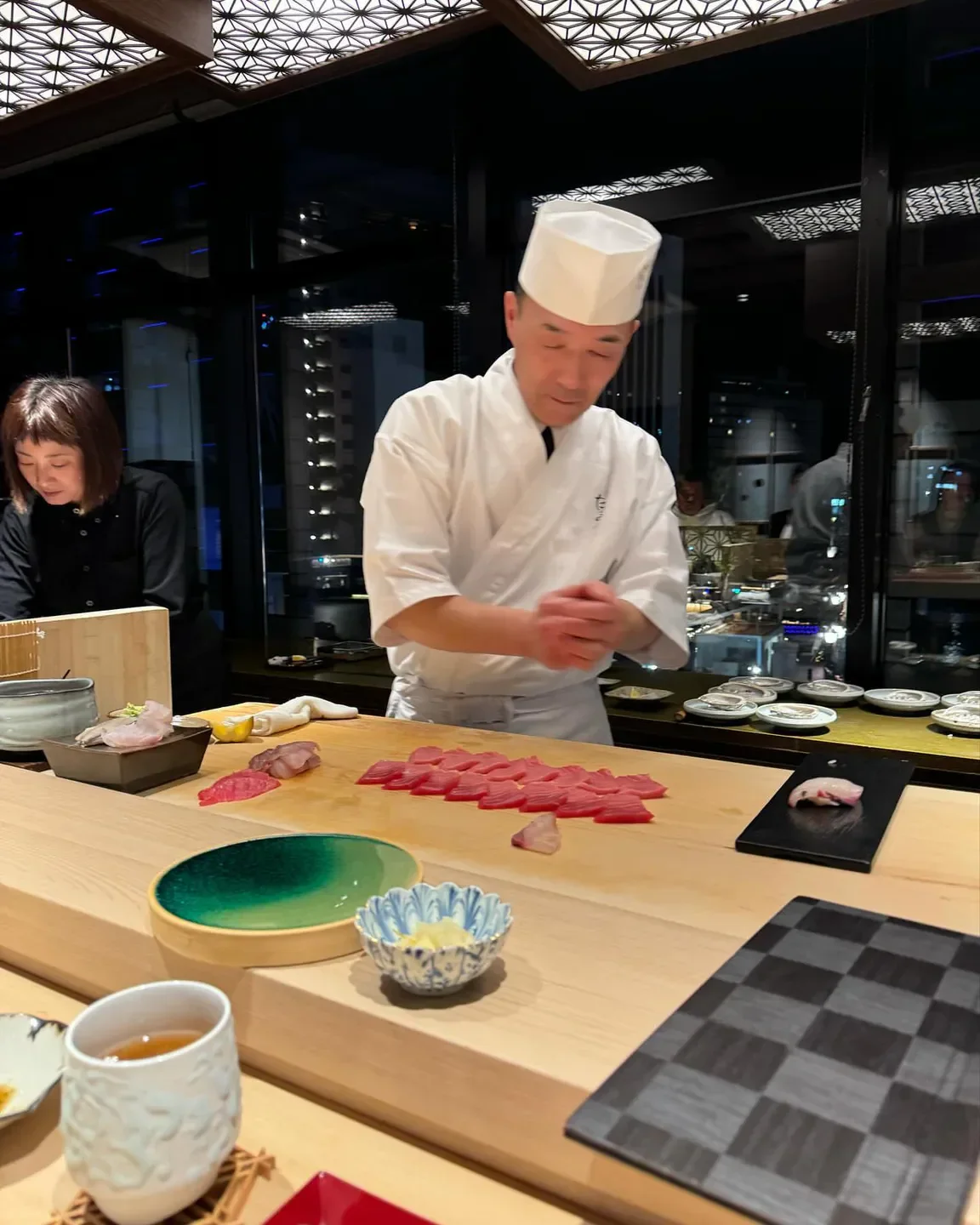 Chef at Imoto restaurant in Fukuoka preparing sushi with fresh ingredients.