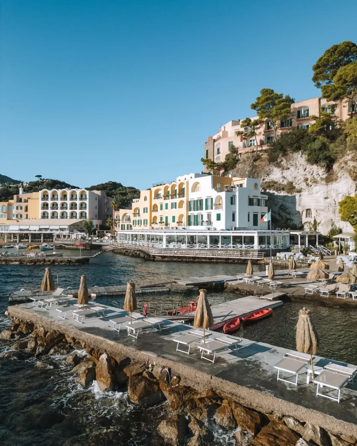 Indaco restaurant in Campania, with pier, umbrellas and waterside views on a sunny day.