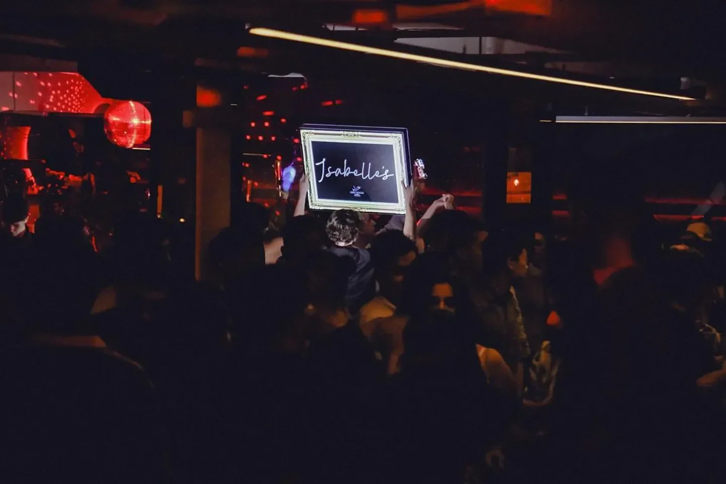 Party scene at Isabelle's nightclub in Toronto with sign held up by the crowd