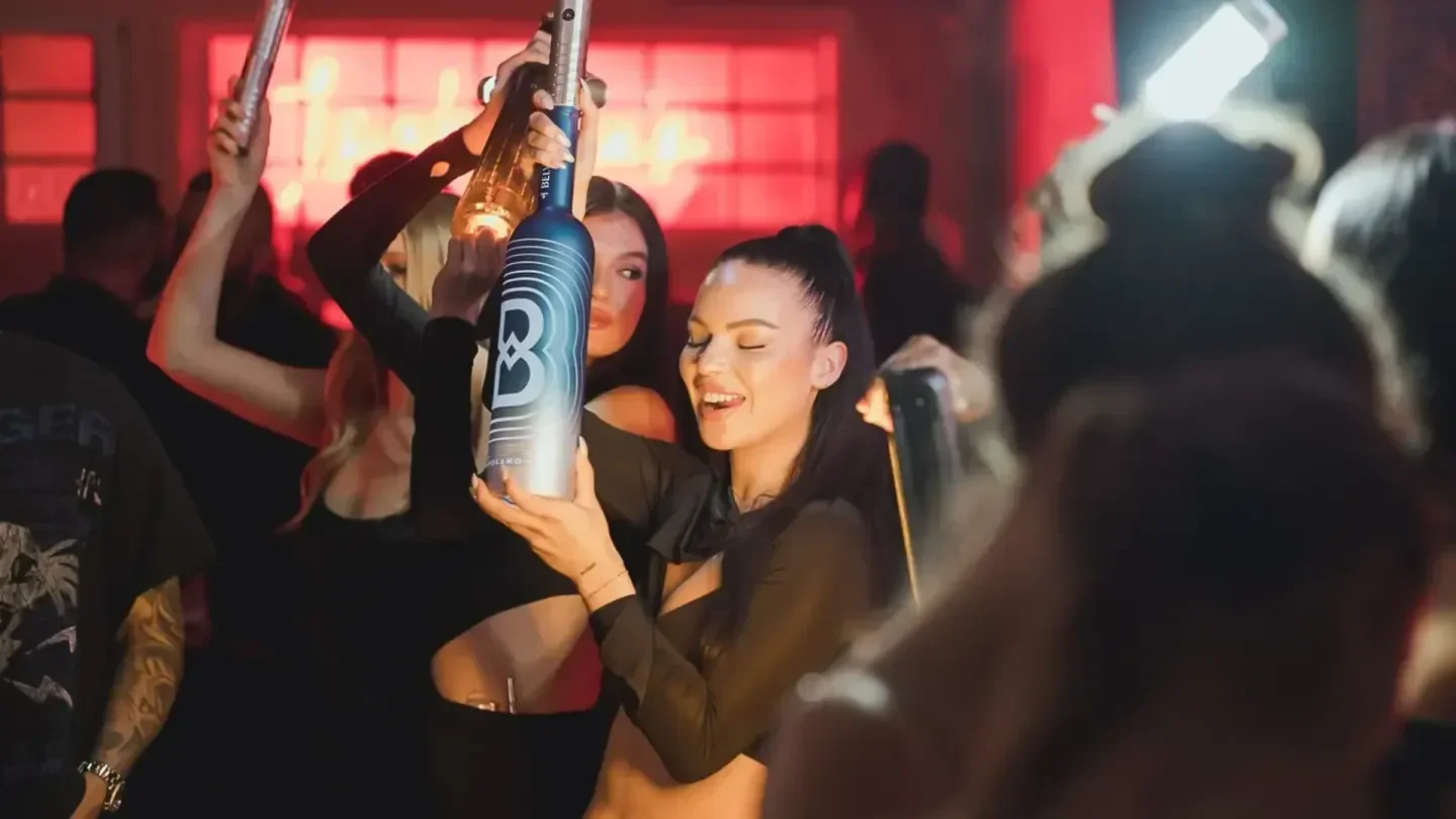 Party at Isabelle's nightclub in Vancouver, with people holding up a bottle of alcohol.