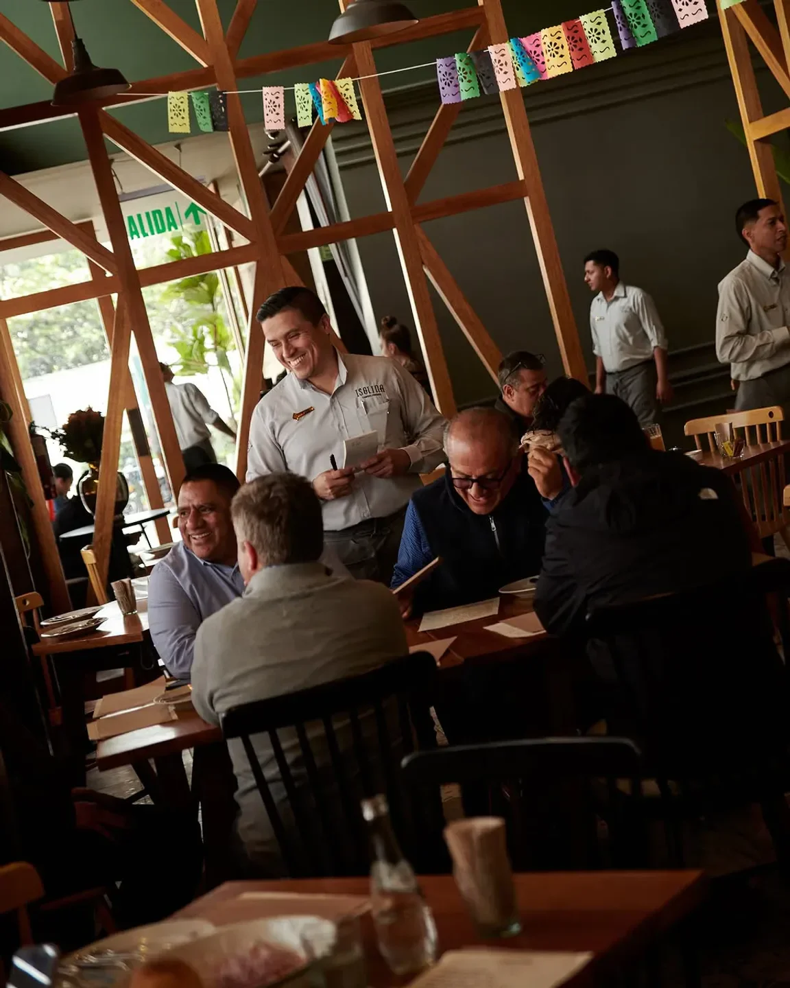 Dining experience at Isolina restaurant in Lima, with waiter serving and guests enjoying.