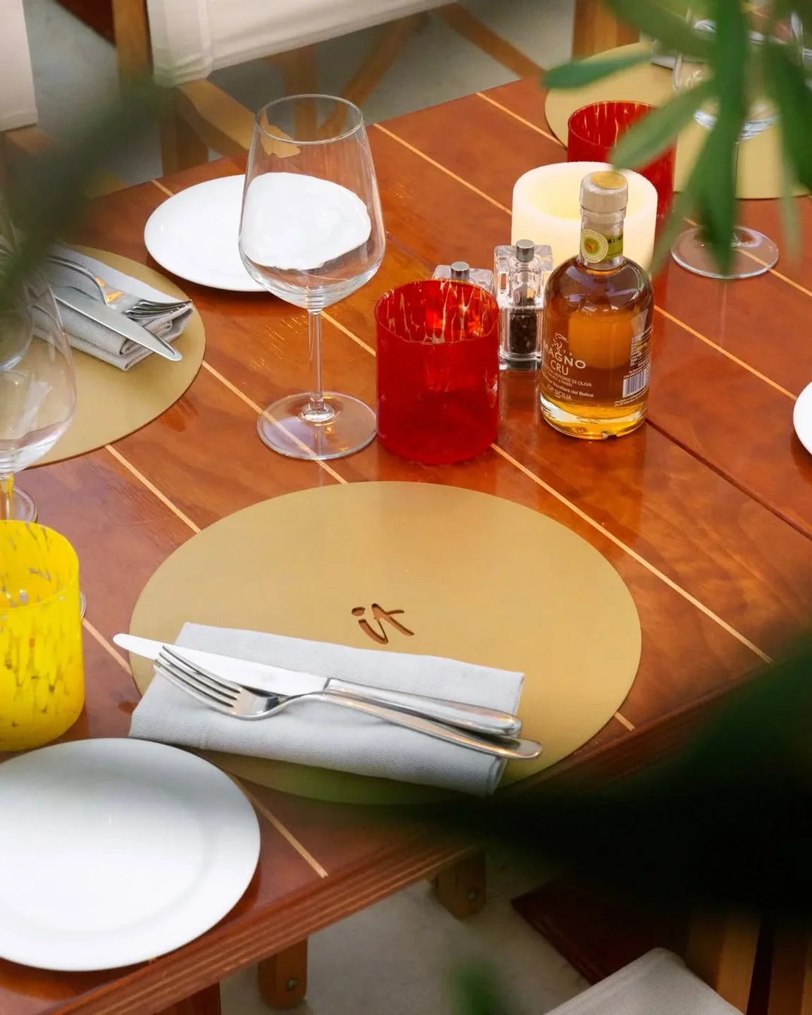 Table setting at IT restaurant in Porto Cervo, IT, with golden placemats and elegant cutlery.
