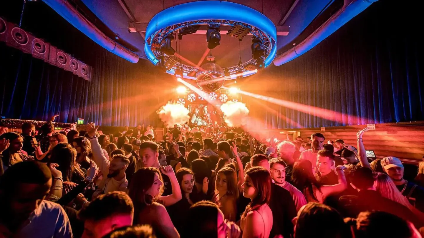 Energetic crowd partying at Jade nightclub in Zurich with lights and a disco ball.