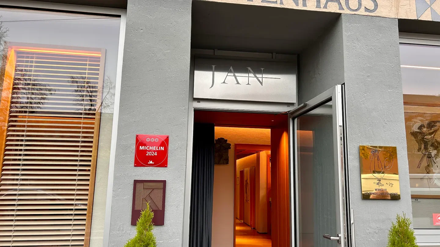Entrance of JAN restaurant in Munich, Germany, with Michelin star recognition and inviting interior.