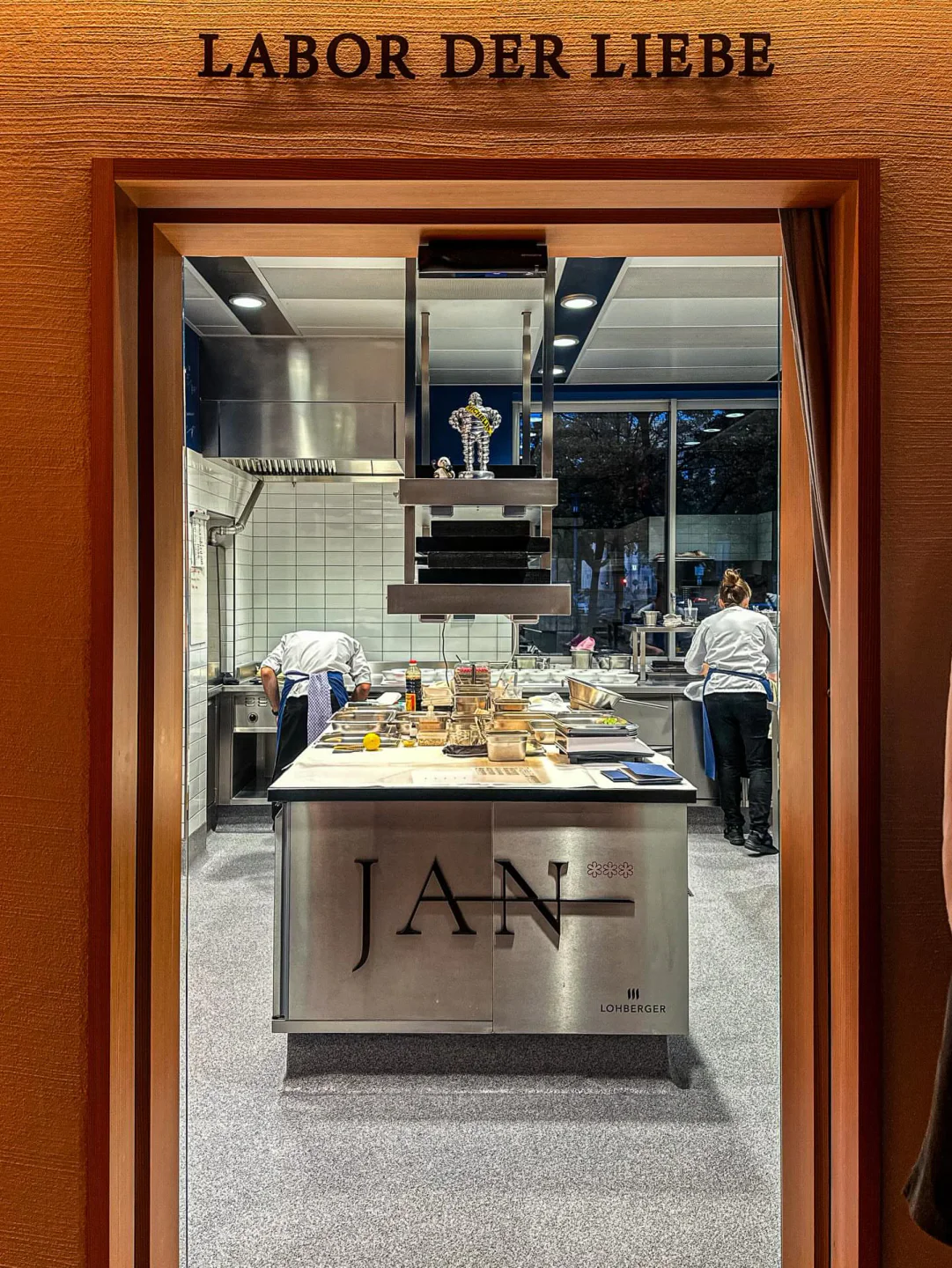 Interior view of the kitchen at JAN restaurant in Munich, Germany, featuring chefs at work.