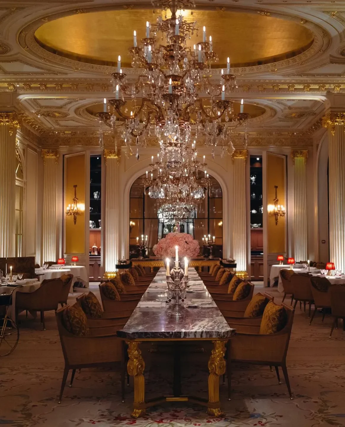Elegant dining room at Jean Imbert restaurant in Paris, featuring a grand chandelier.