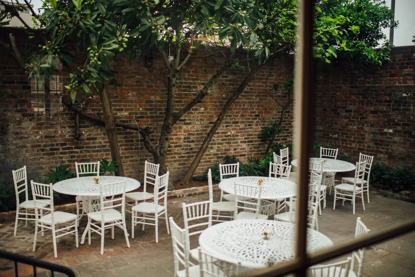 Patio seating at Jewel of the South restaurant in New Orleans, brick wall backdrop.