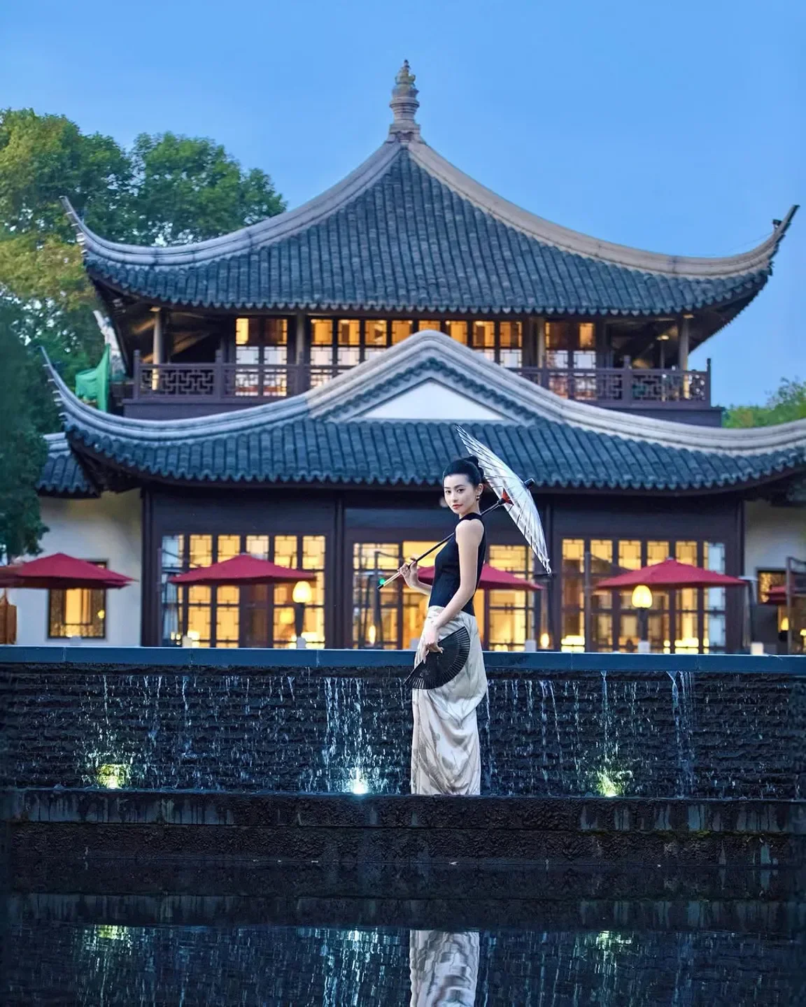 Woman with umbrella at Jin Sha restaurant in Hangzhou, China, with traditional architecture