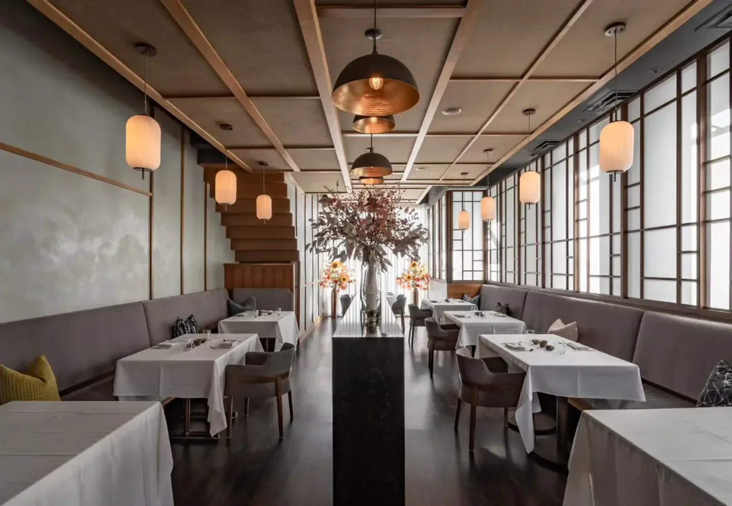 Interior of Jinsei Motto restaurant in Chicago, featuring tables, lighting, and staircase.