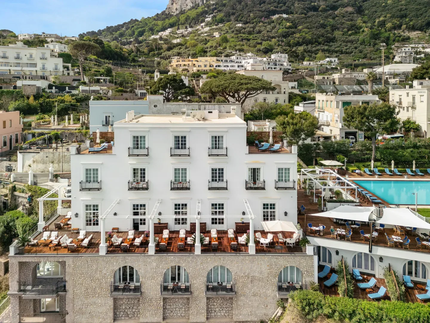 Exterior view of JKitchen Restaurant in Capri with restaurant seating and mountain backdrop.