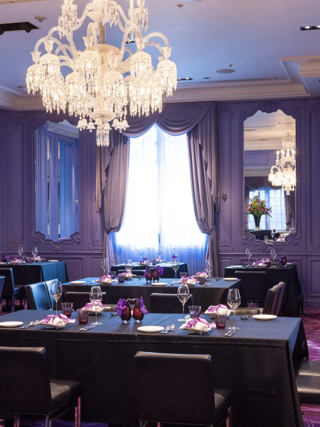 Elegant dining room interior at Joël Robuchon Restaurant in Tokyo, featuring chandeliers and prepared tables.
